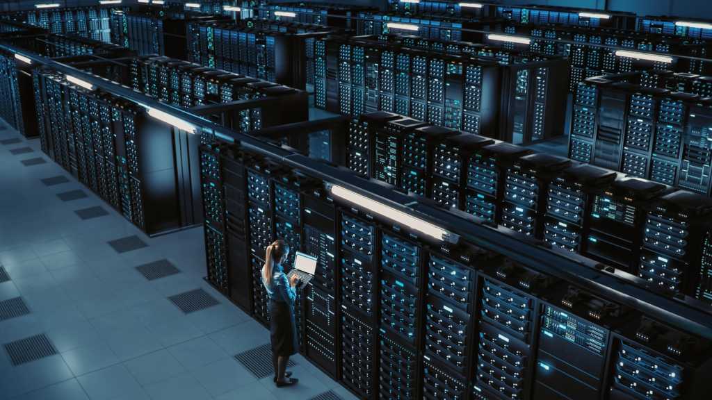 3D Computer Graphics: Data Center Female Chief Technology Officer Using Laptop Standing In Warehouse, Activates Servers, Information Digitalization Starts. SAAS, Cloud Computing, Online Service